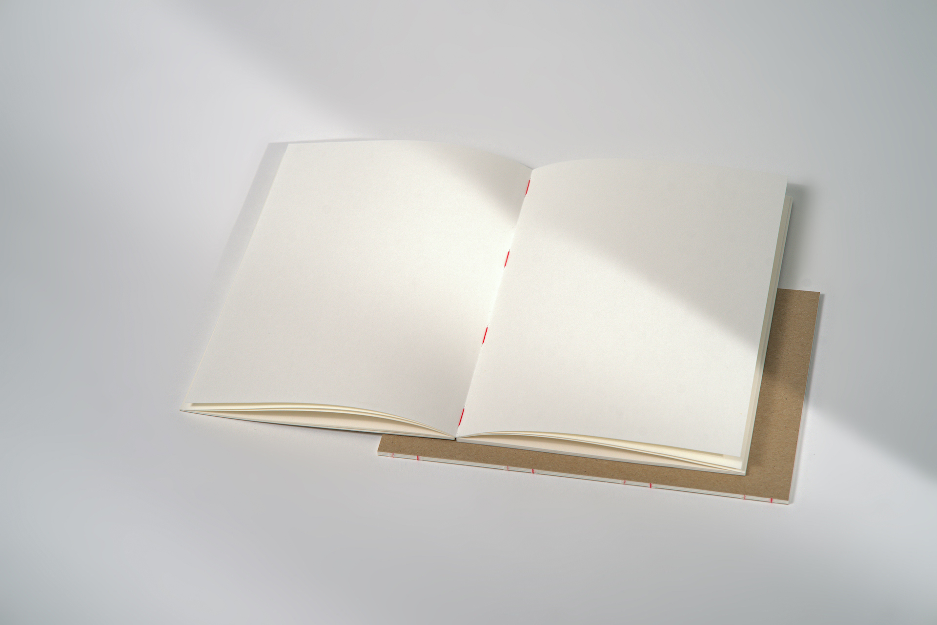 Fadengeheftetes Skizzenbuch in A5-Größe mit 48 Seiten aus naturweißem, 120g starkem Zeichenpapier und festem Einband aus Recyclingkarton. Liegt geöffnet flach auf.